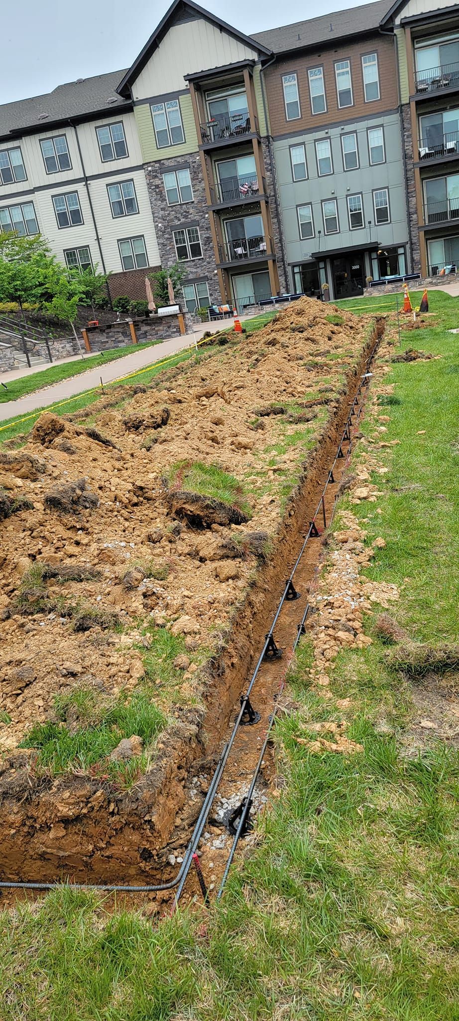 A large building is behind a large pile of dirt and grass.