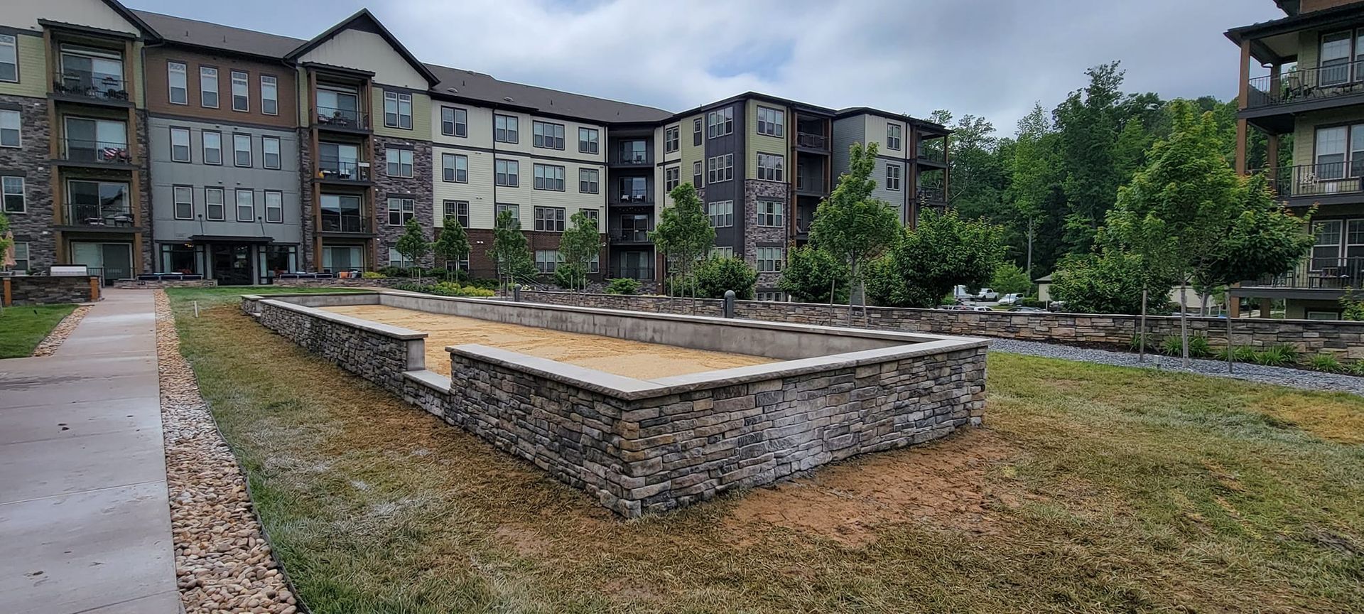 A large apartment building with a sandbox in front of it.