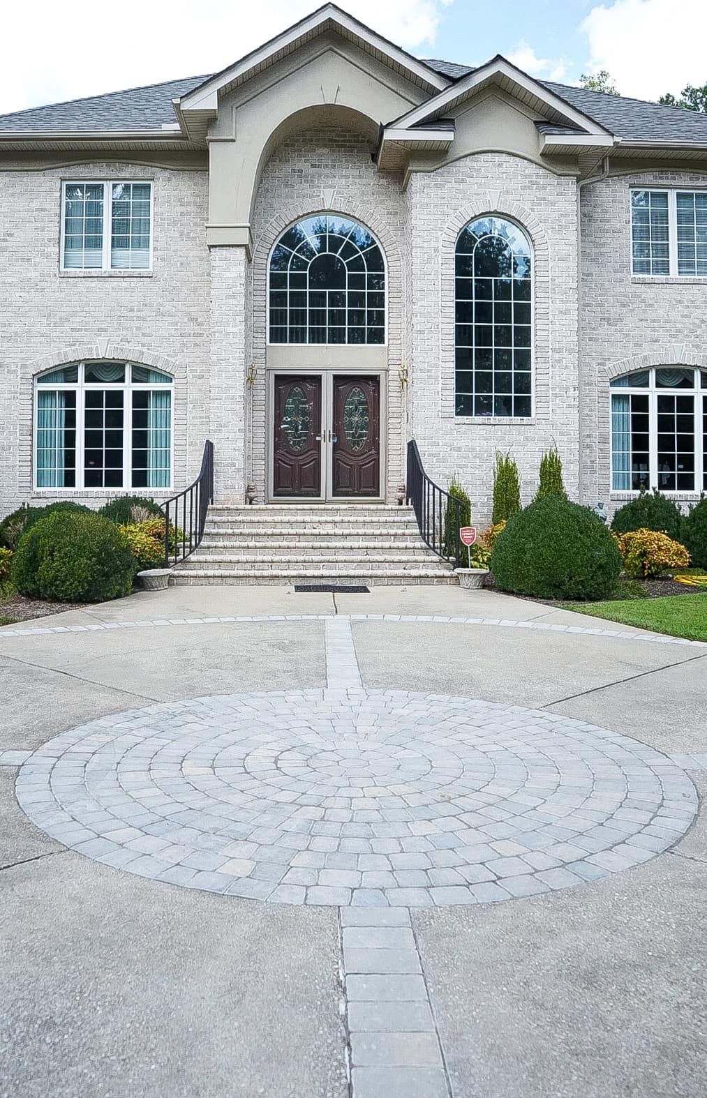 A large brick house with a circular driveway in front of it.