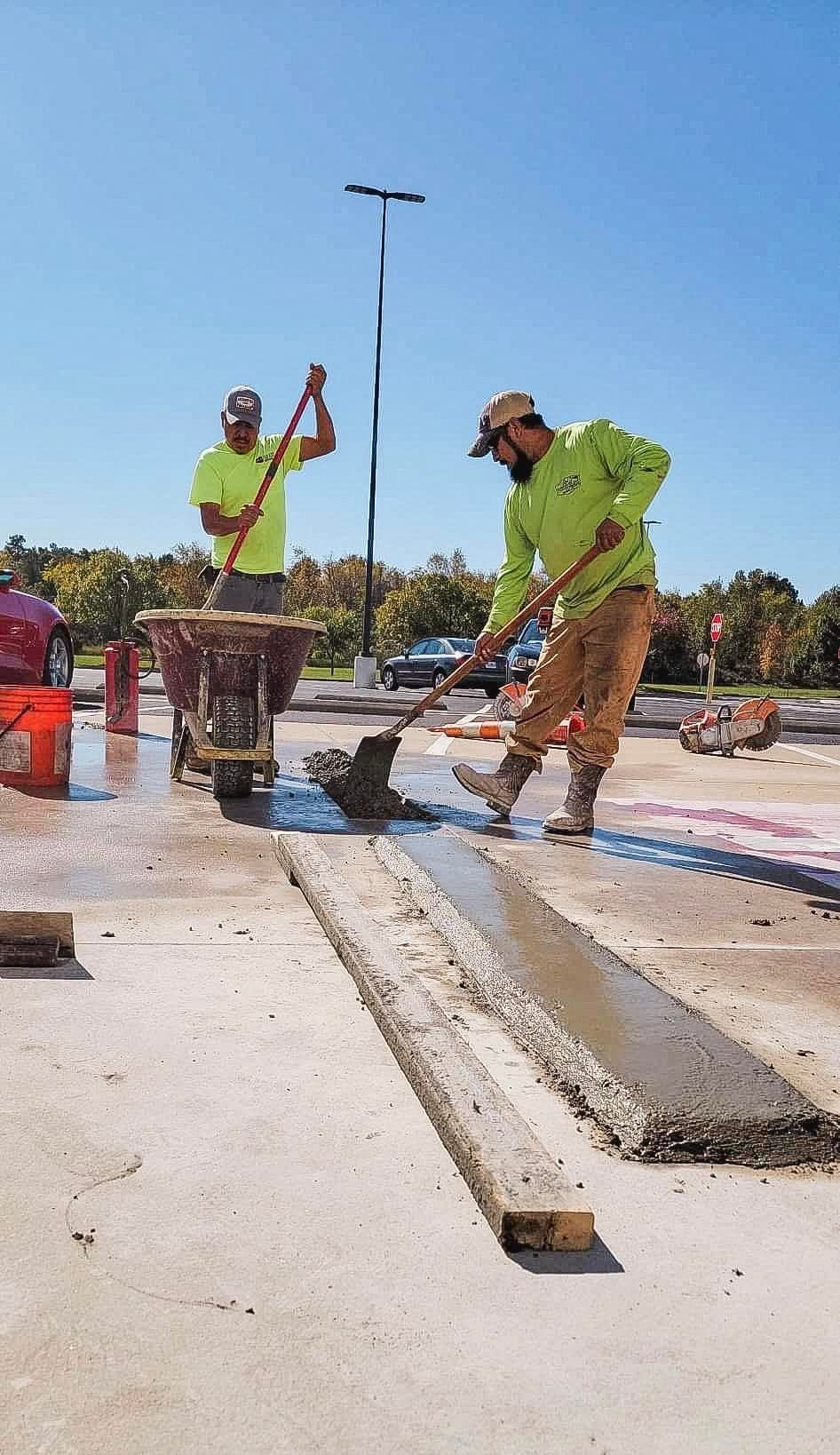 Two construction workers are working on a concrete surface.