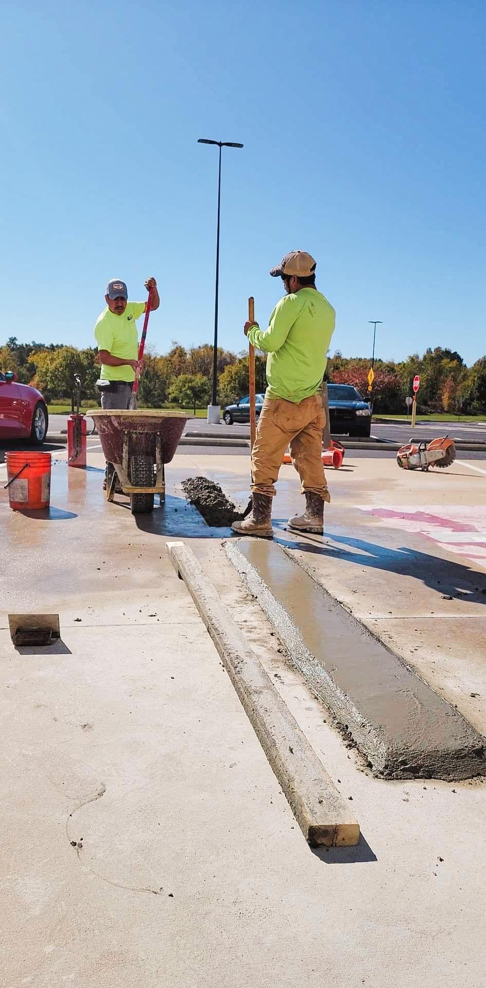 Two construction workers are working on a parking lot.