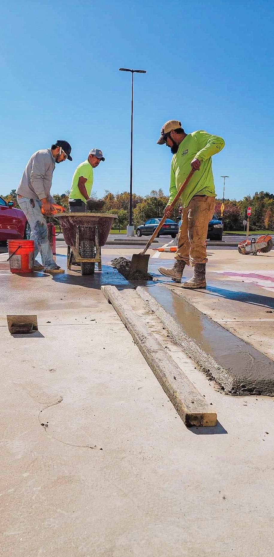A group of construction workers are working on a parking lot.