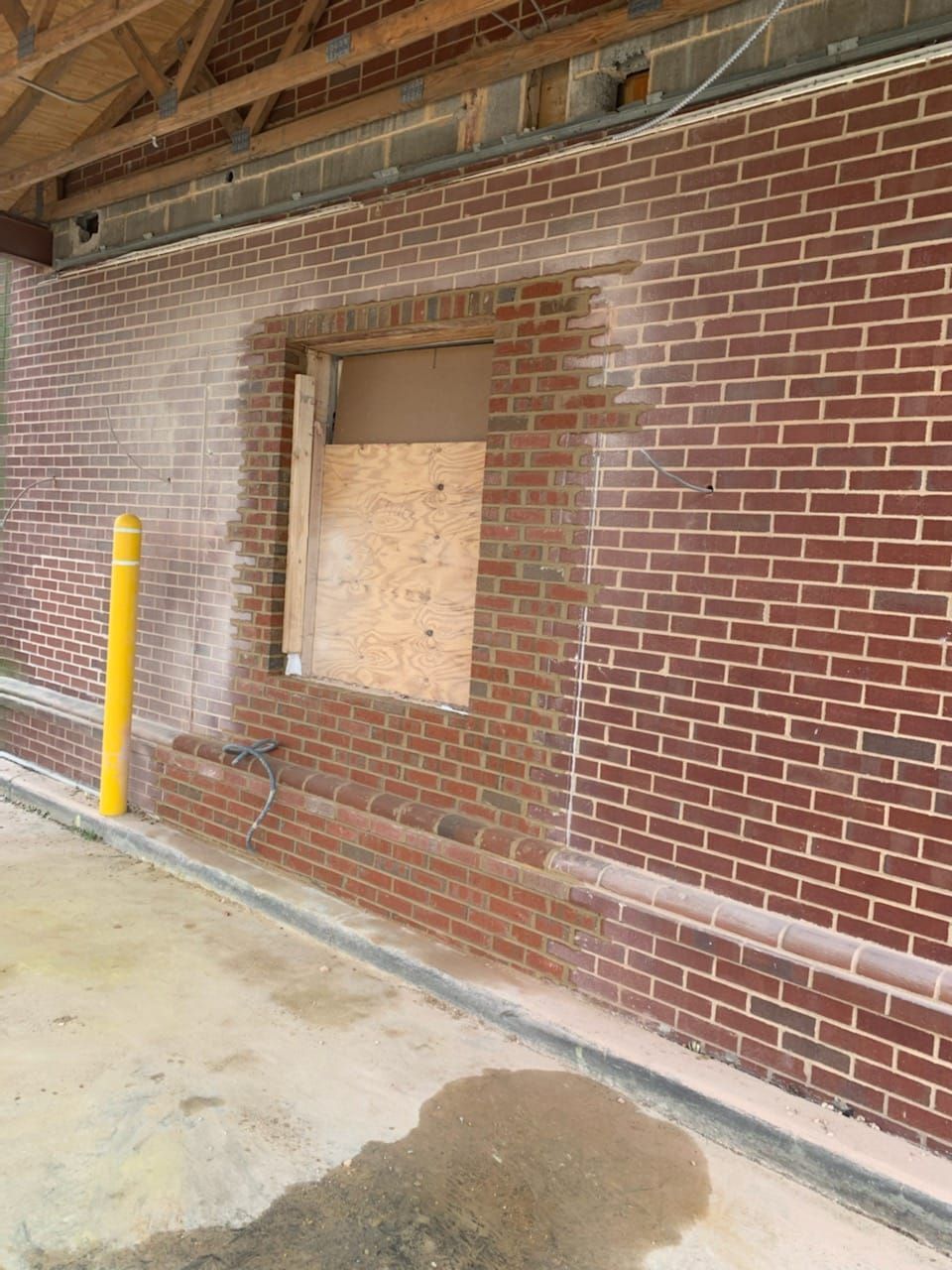 A brick wall with a hole in it and a window.