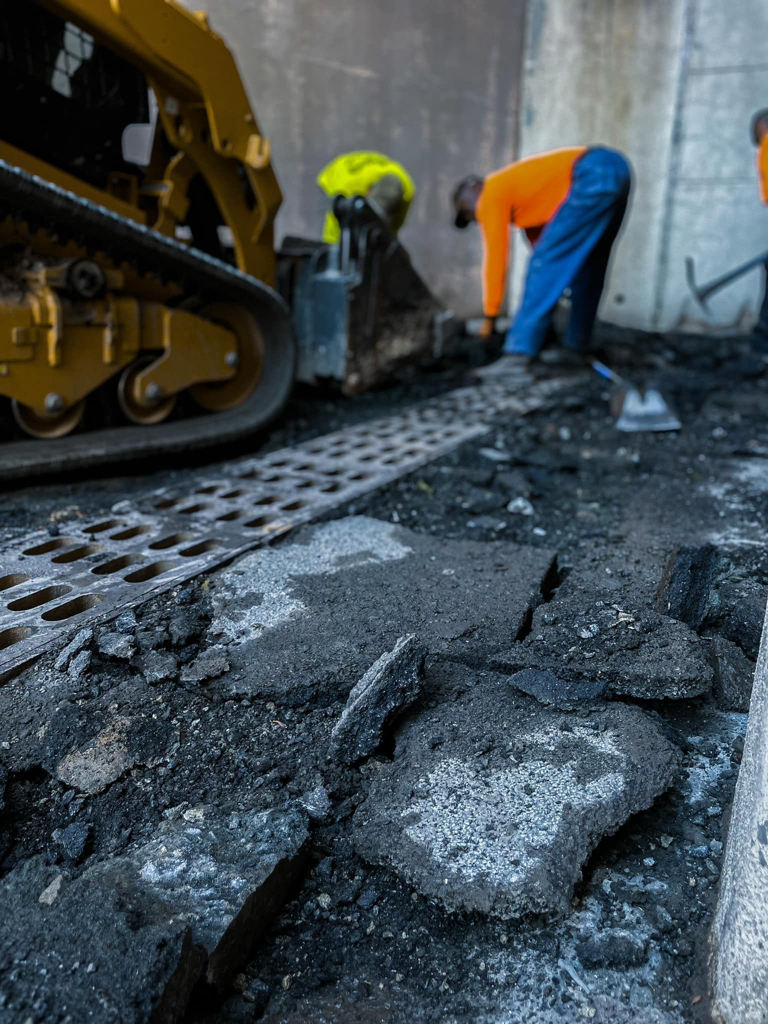 A man is working on a road with a bulldozer in the background.