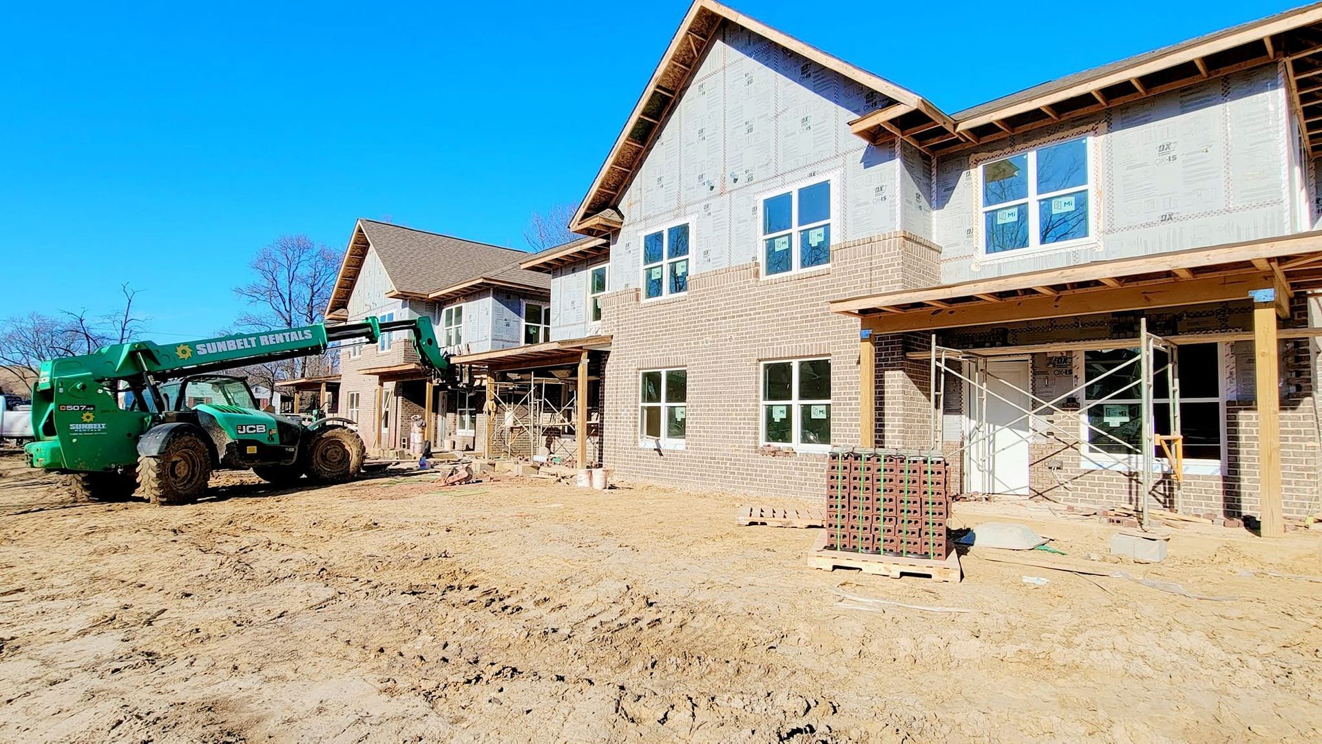 A green tractor is parked in front of a building under construction.