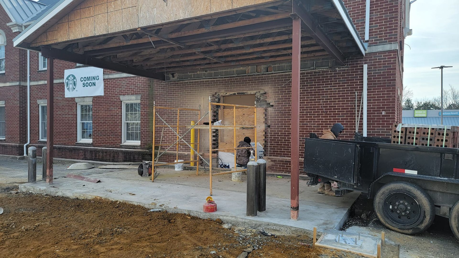 A truck is parked in front of a brick building under construction.