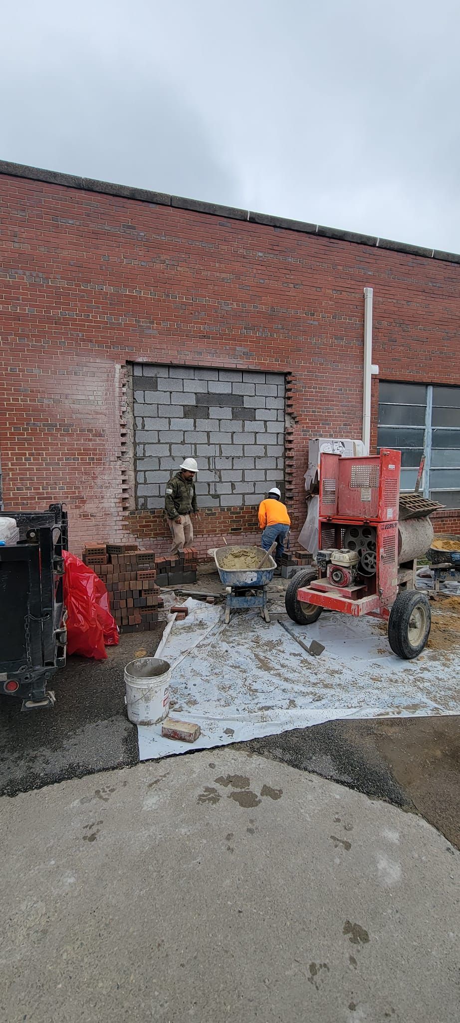 A red tractor is parked in front of a brick building.