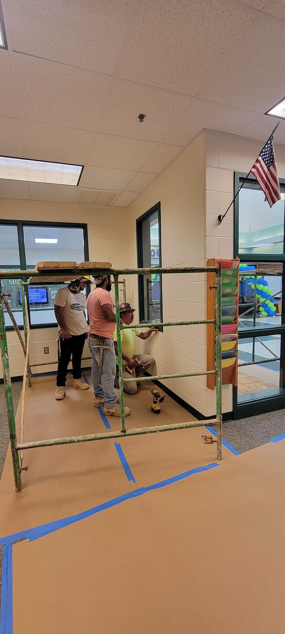 A group of people are working on a wall in a room.