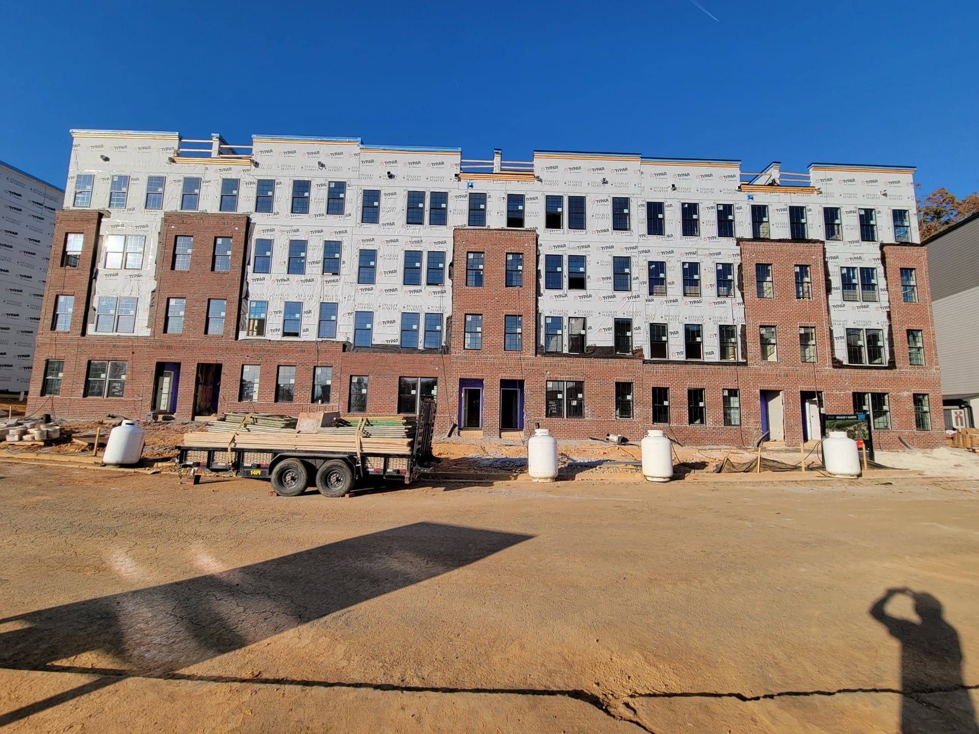 A large brick building is being built in a dirt field.