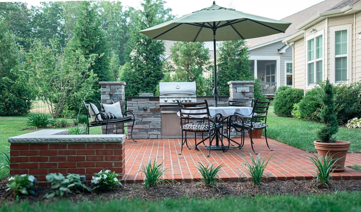 A Patio With a Table and Chairs and an Umbrella in Front of a House
