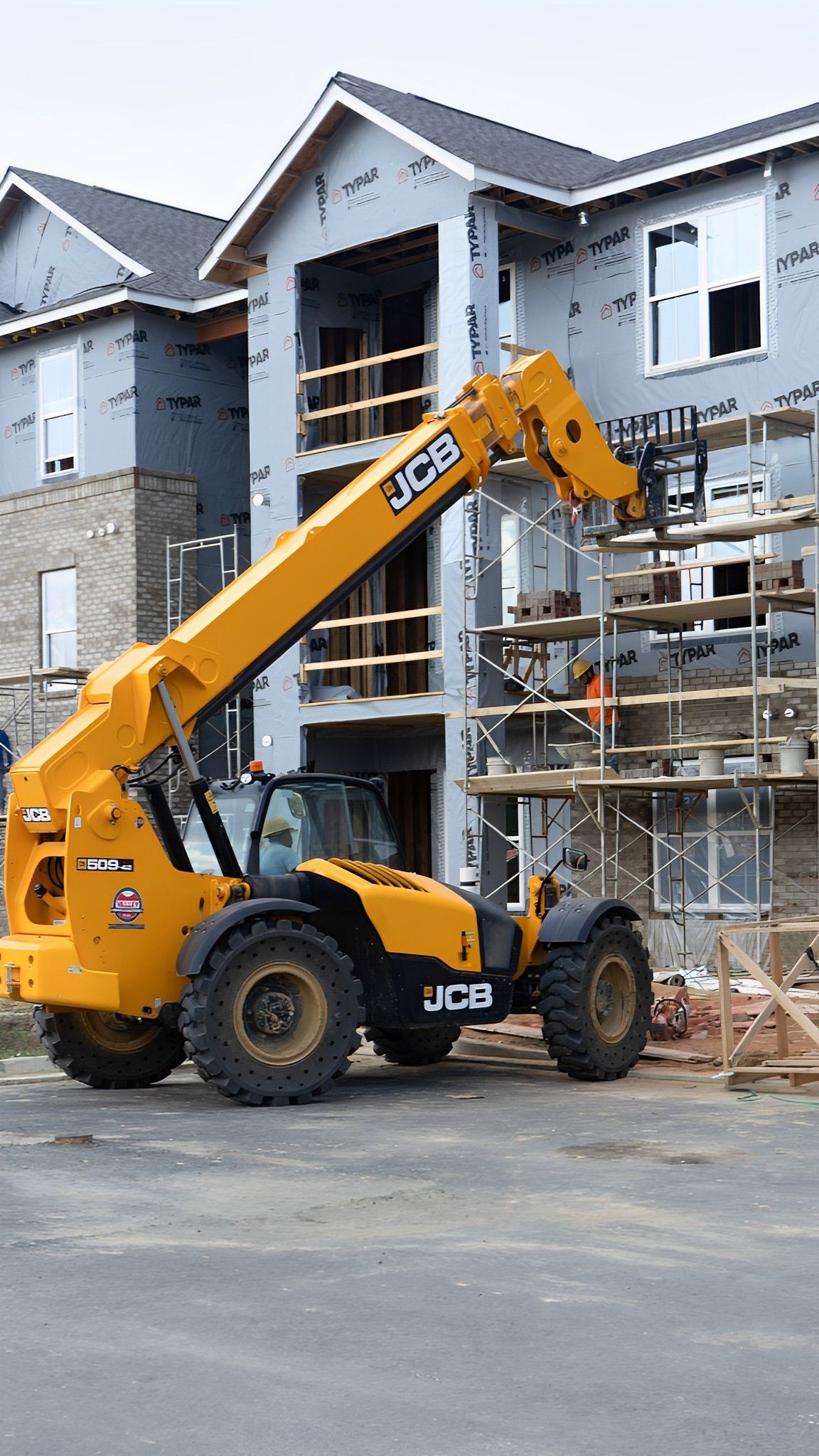 A yellow forklift is parked in front of a building under construction.