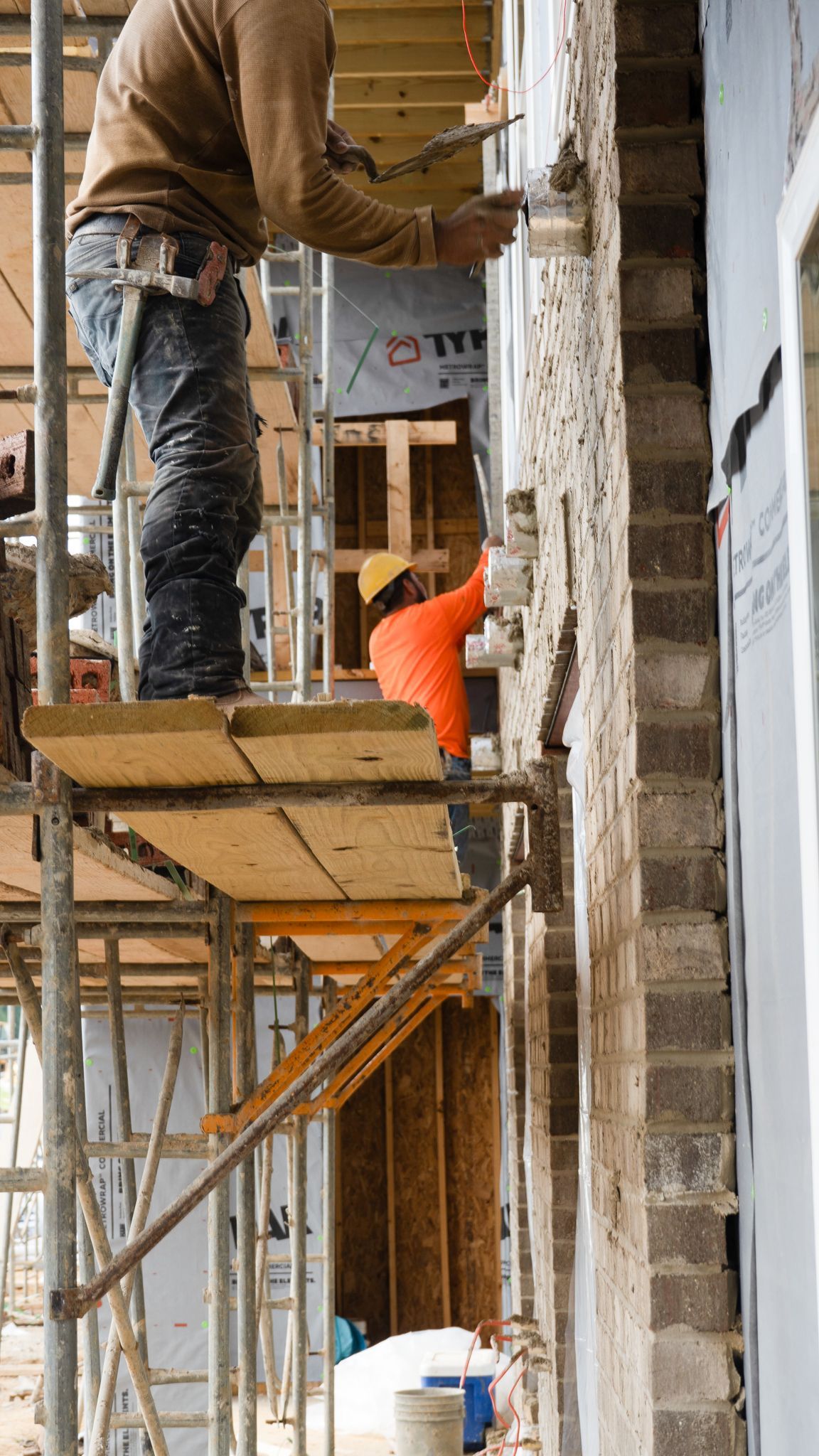 A group of construction workers are working on a building on scaffolding.