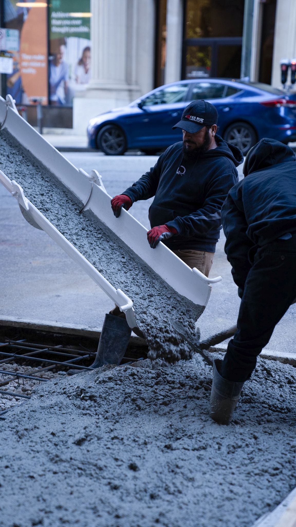 A group of construction workers are pouring concrete on a sidewalk.