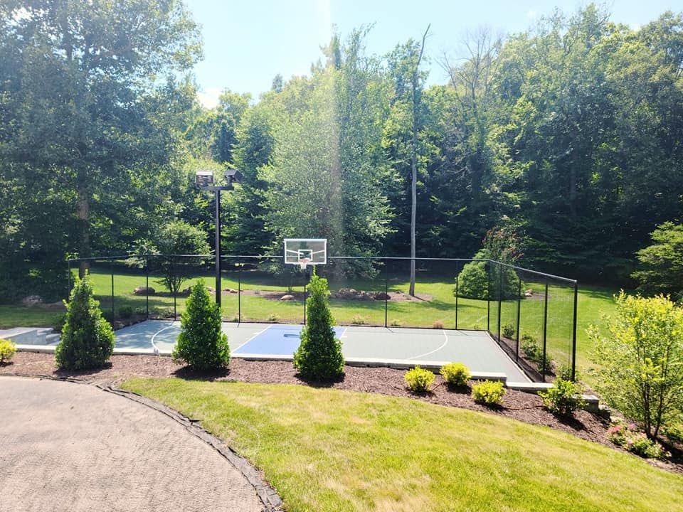 A basketball court in a backyard with trees in the background