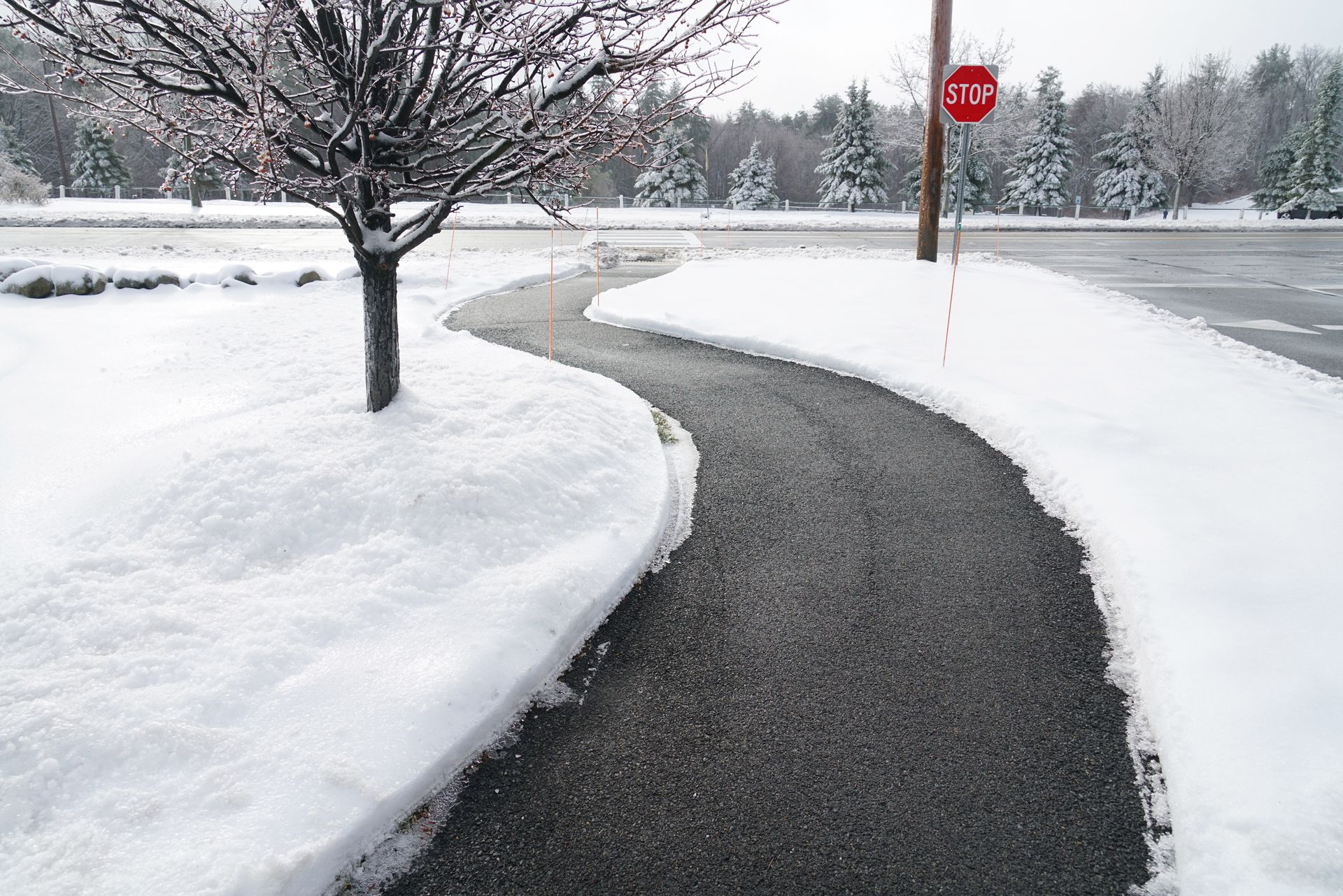 A Snowy Sidewalk With a Stop Sign in the Background