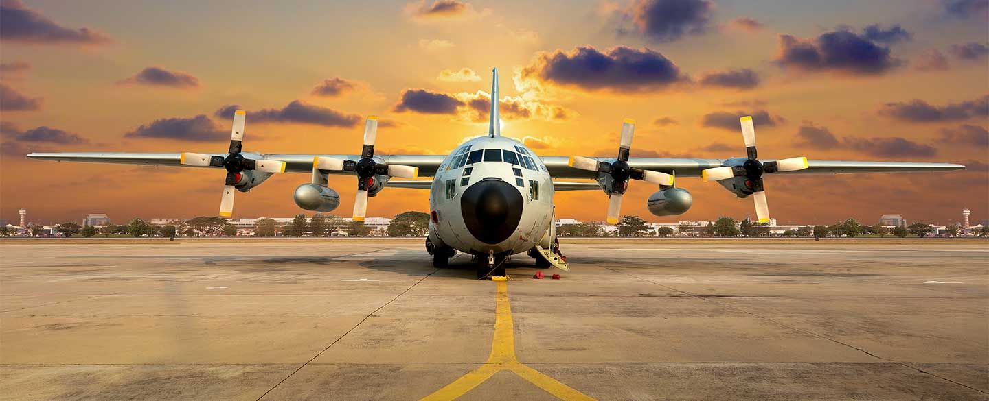 Military aircraft on tarmac at golden-hour sunset