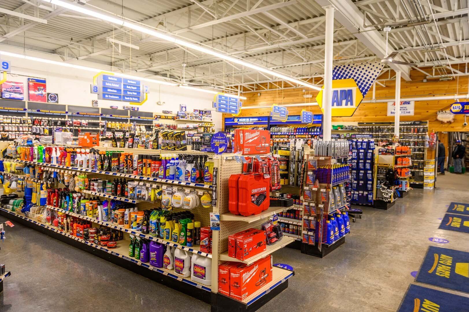 A bright, spacious NAPA auto parts store with aisles of neatly organized shelves containing various automotive products.