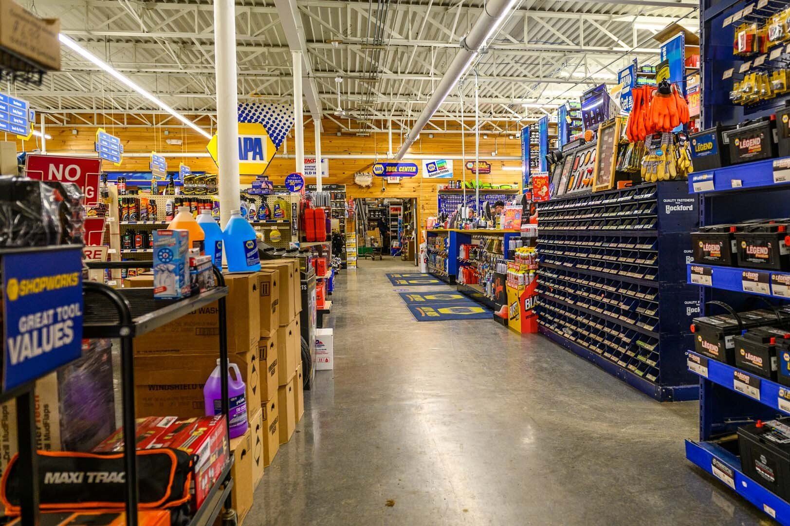 A brightly lit interior of an auto parts store with aisles of products, including boxed goods and shelves of car parts.