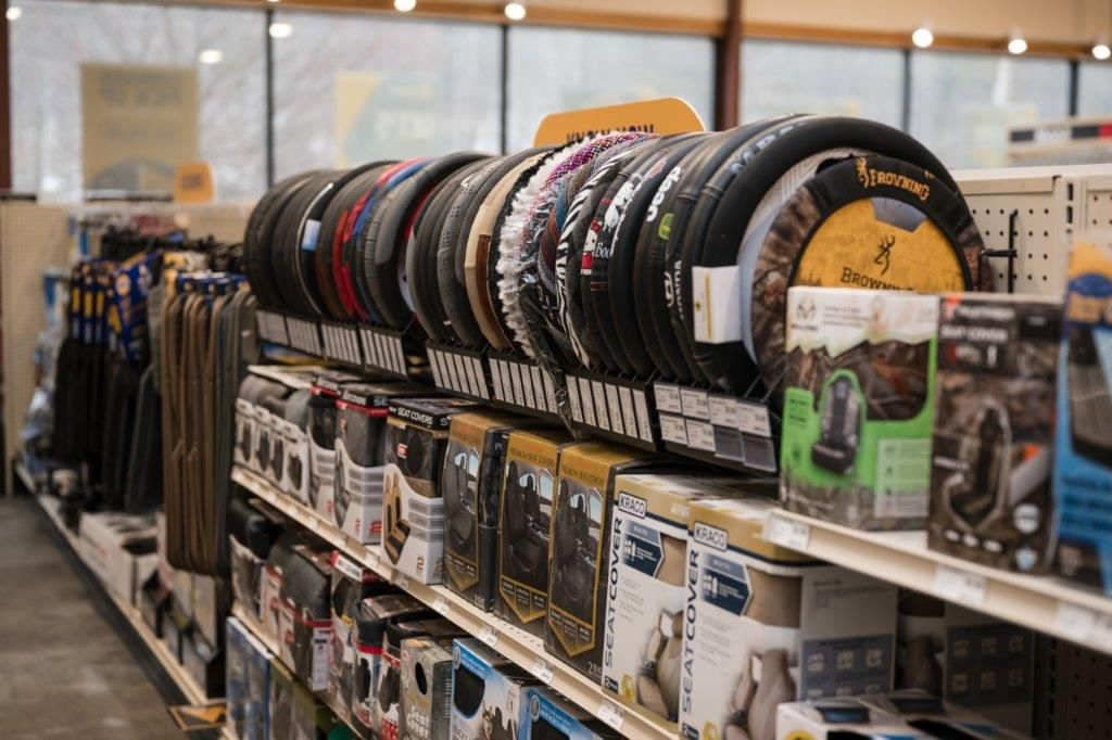 A store aisle displaying various circular car steering wheel covers hanging on a rack above shelves of automotive products.