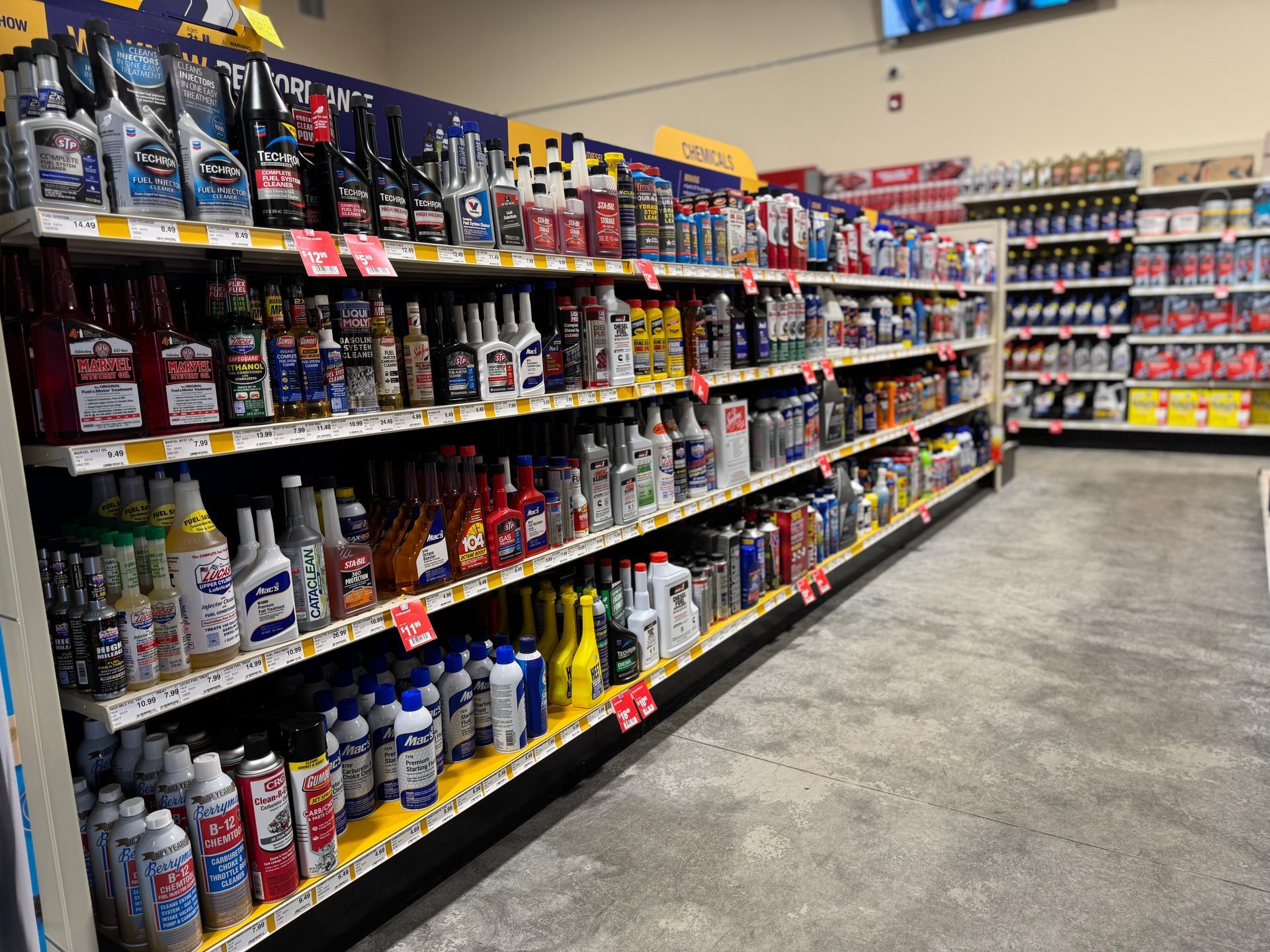 Shelves in a retail store stocked with various automotive cleaning, maintenance, and fluid products.