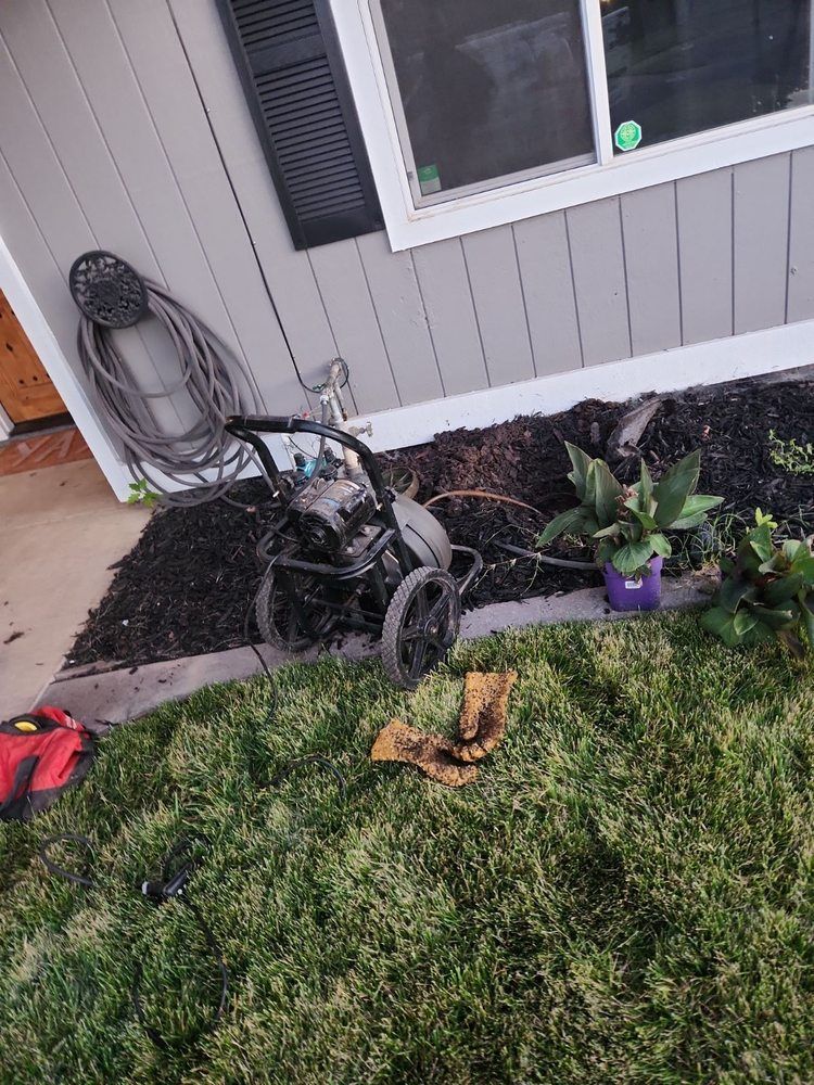 Burnt yard equipment beside a house wall with blackened mulch and damaged plants
