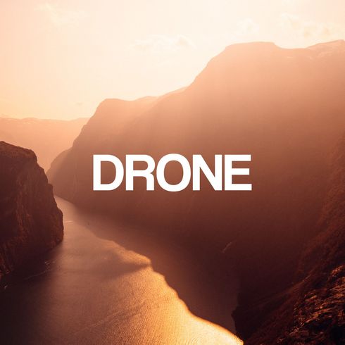 Tekst «Drone» lagt over et naturskjønt landskap, med fjell og et vann, badet i varmt, gyllent lys.