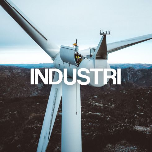 Vindturbin mot en fjellrik bakgrunn med ordet «INDUSTRI» overlagt.