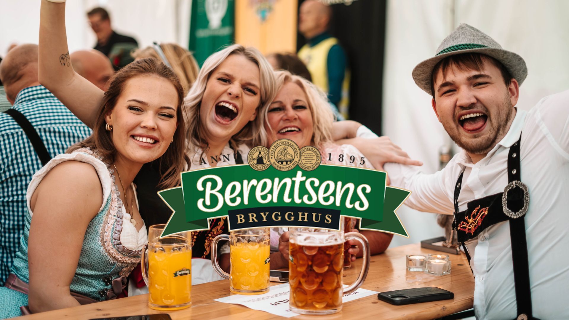 Fire personer ved et bord, smilende og ropende med ølkrus på et arrangement i Oktoberfest-stil, under en logo for Berentsens brygghus.