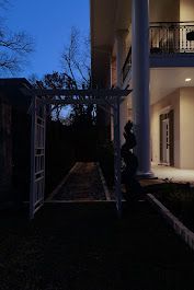 A large house with a pergola in front of it at night.