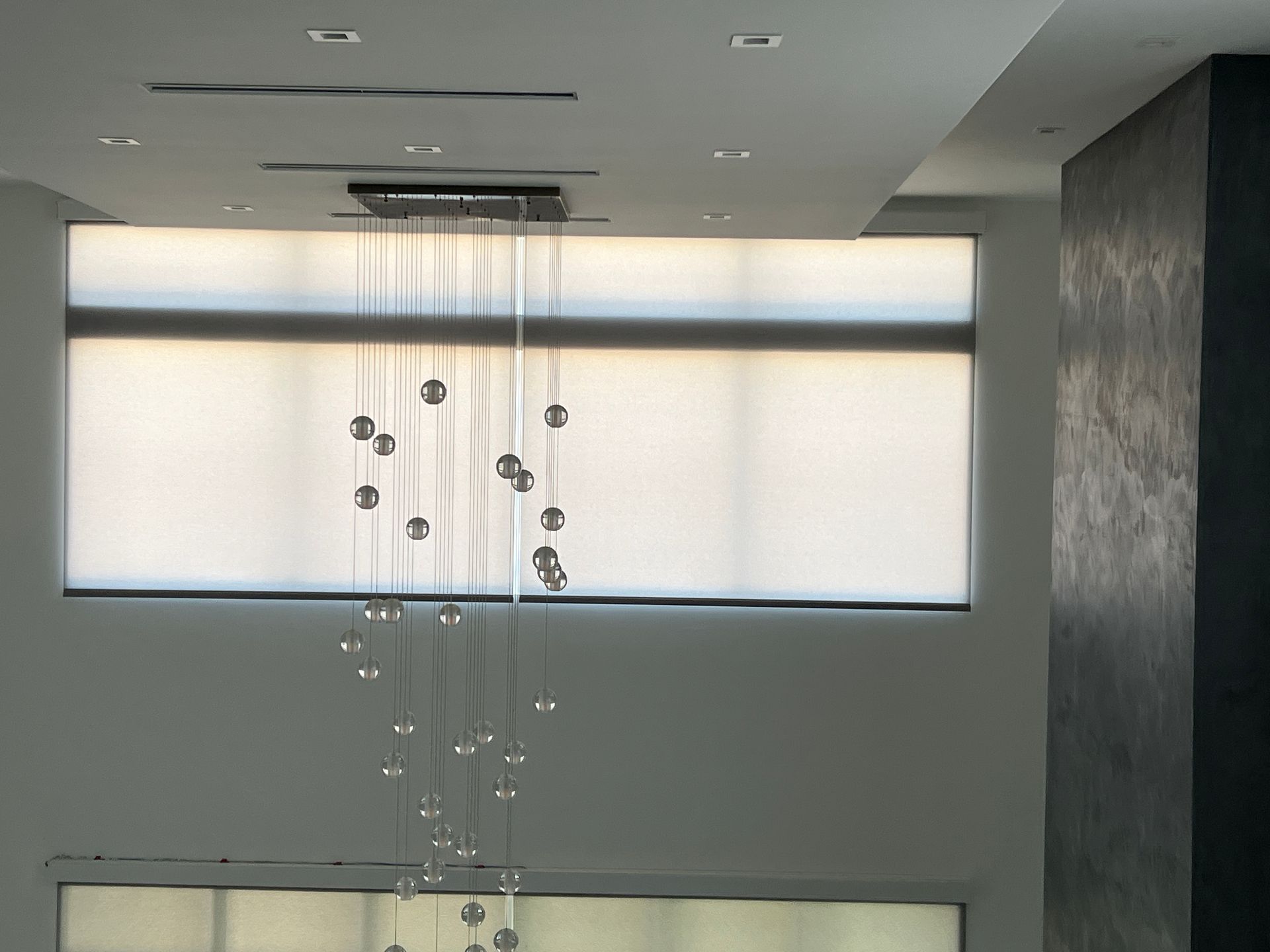 A chandelier is hanging from the ceiling above a window.    