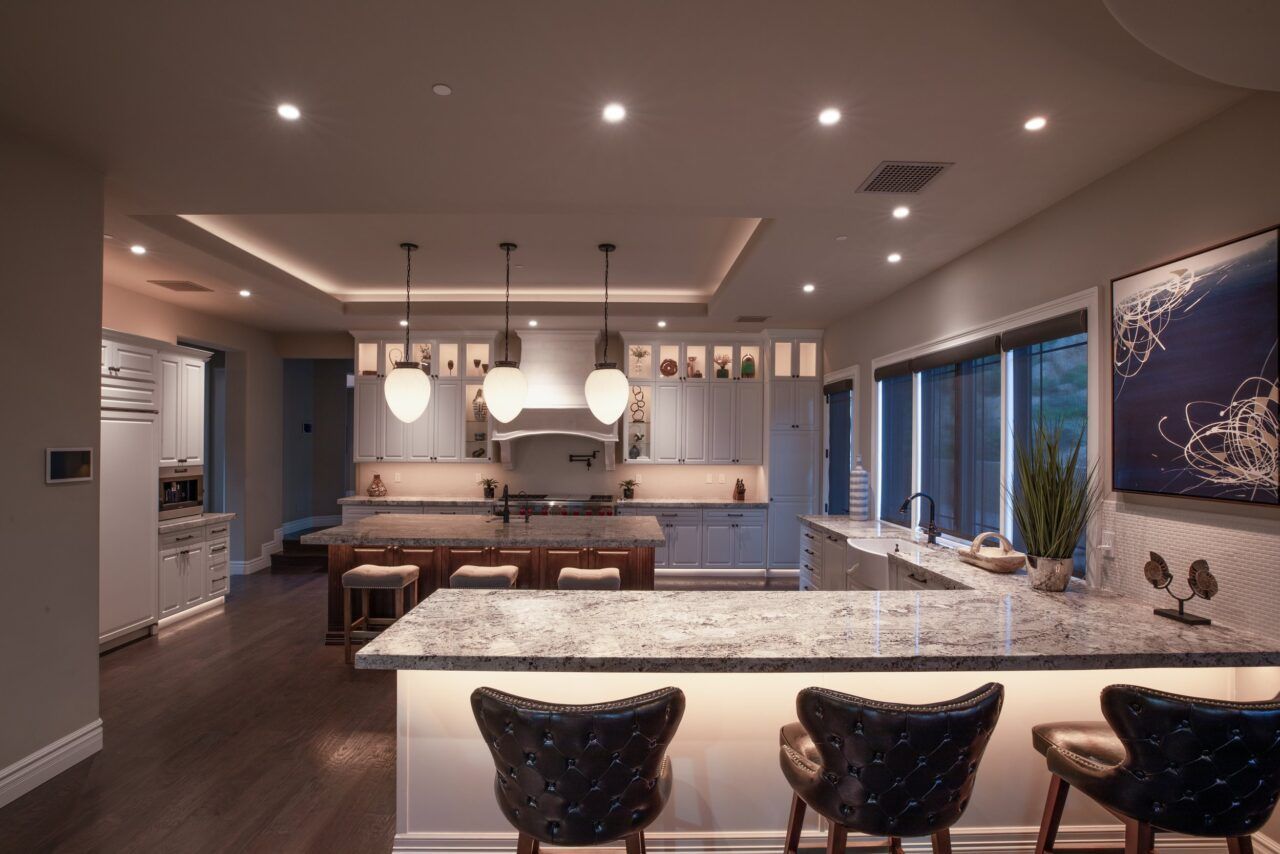 A kitchen with a large island and three bar stools. Premier Lighting & Home Automation, LLC in Dallas Fort Worth (DFW).