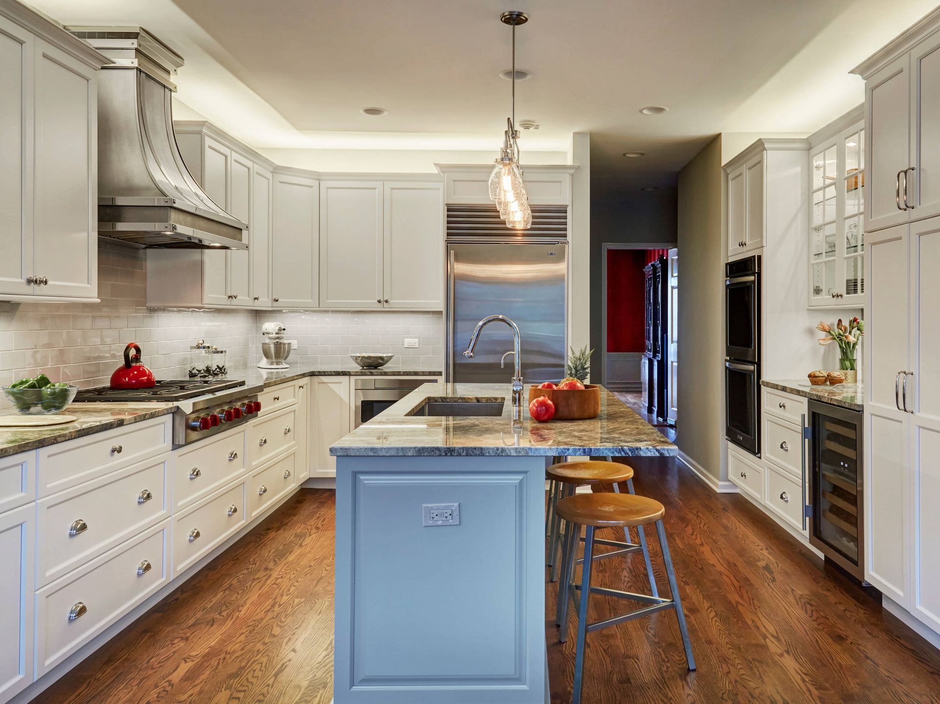 A kitchen with white cabinets , stainless steel appliances , and a blue island.   