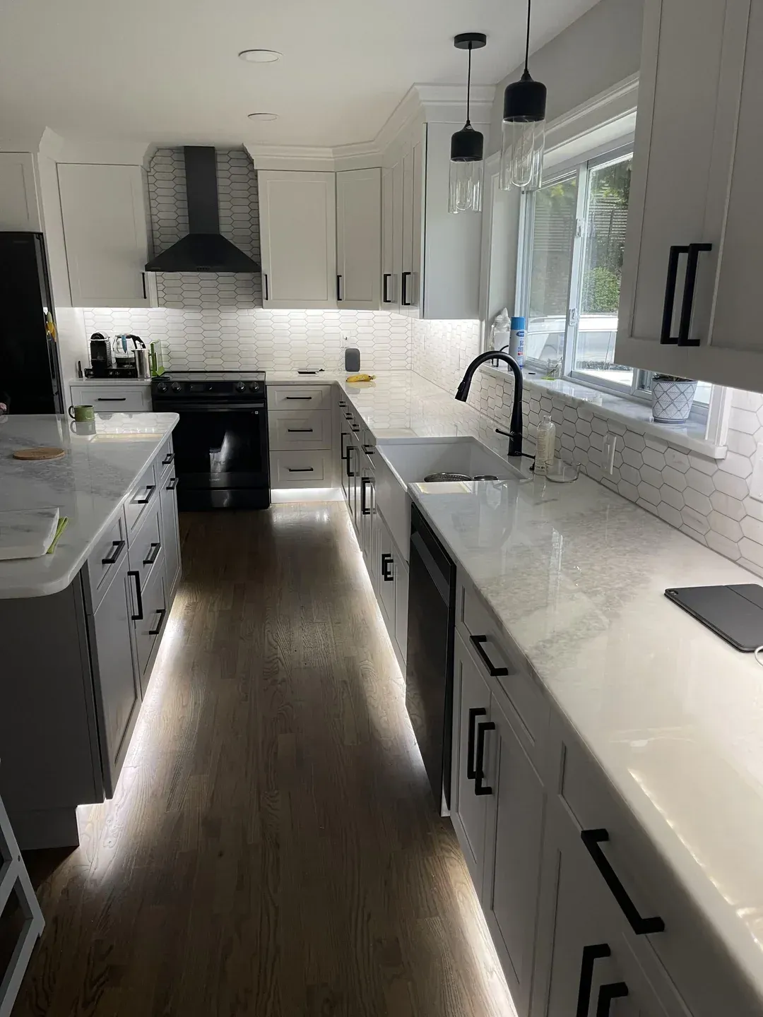 A kitchen with white cabinets , a sink , a stove , and a window.  