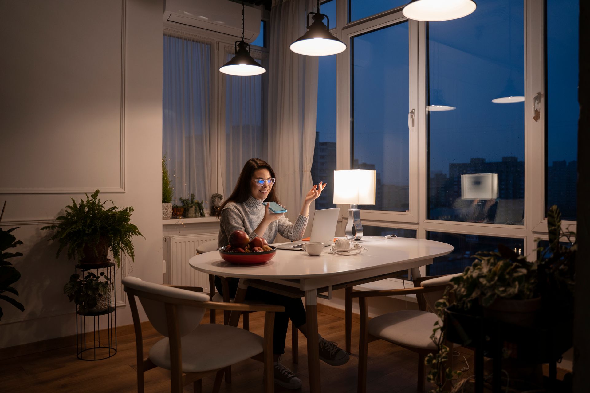 A woman is sitting at a table with a lighting control. Premier Lighting & Home Automation in Dallas Fort Worth (DFW).