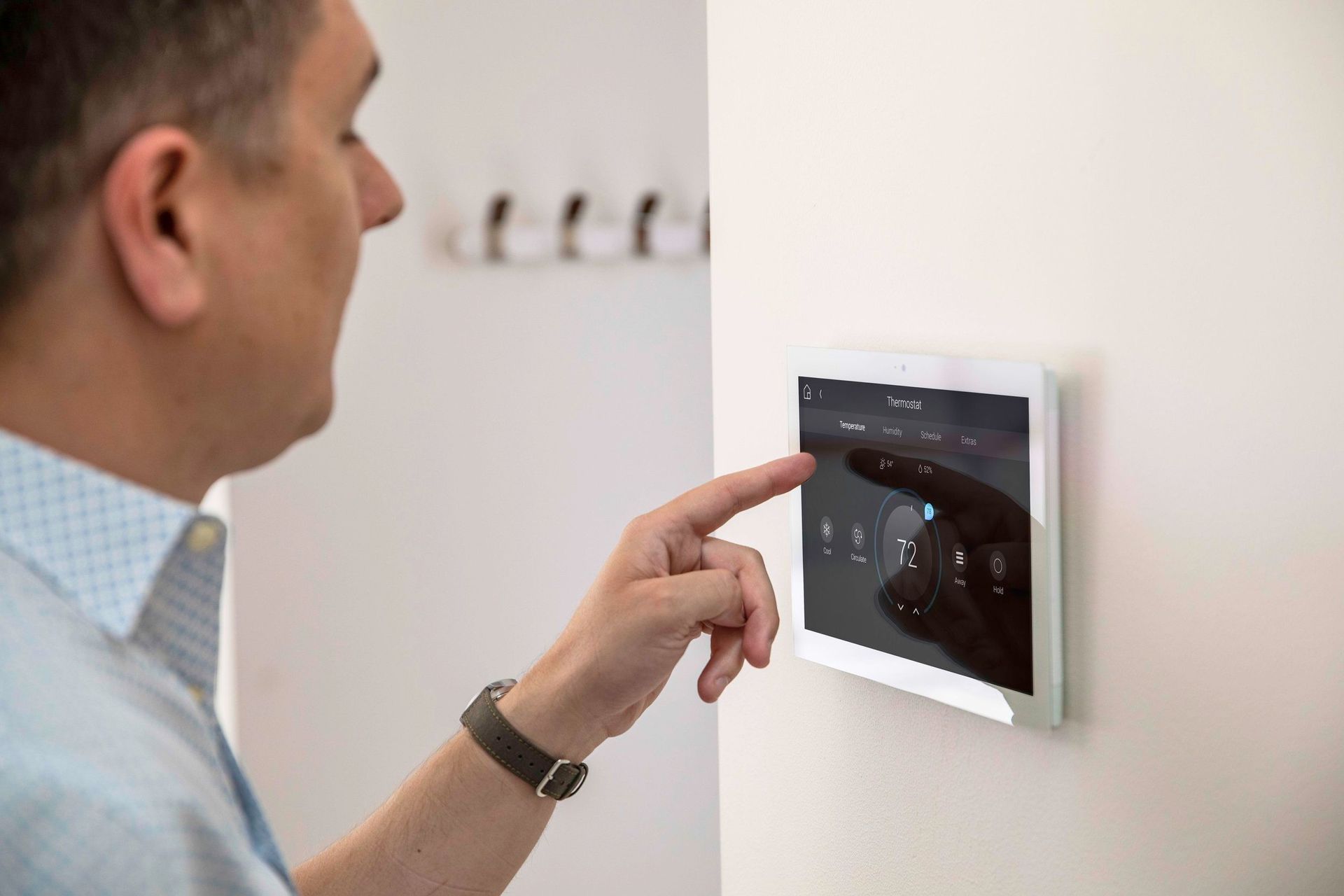 A man is using a tablet to control a thermostat. Portfolio for Premier Lighting & Home Automation home automation Dallas automation systems.