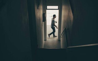A man is walking down stairs in a dark hallway.  Premier Lighting & Home Automation in Dallas Fort Worth (DFW).