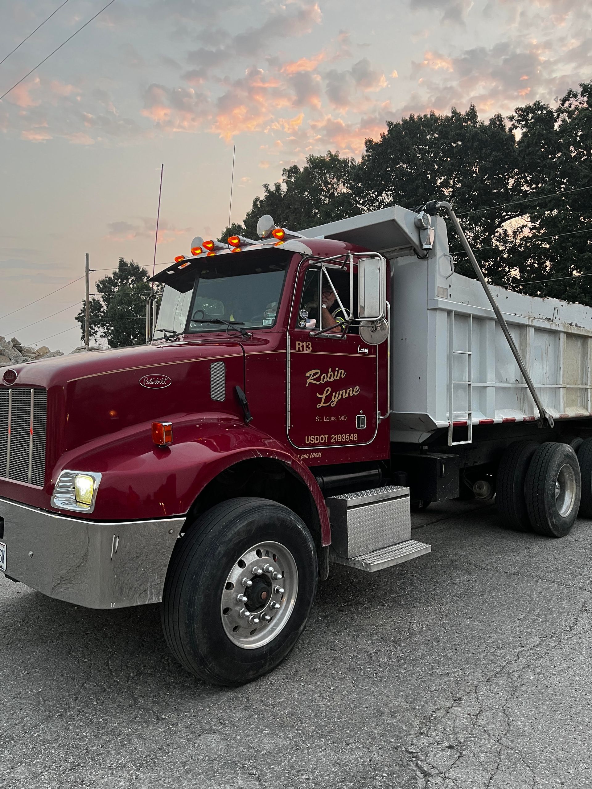 Red dump truck with white bed parked outdoors at dusk under a cloudy sky