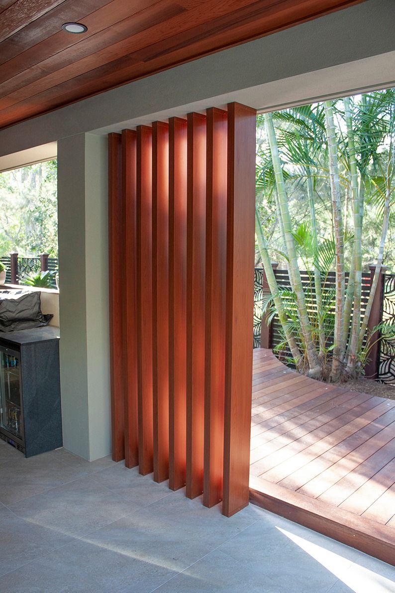 A floor-to-ceiling wooden slatted privacy screen installed in an open-air porch area overlooking a garden. — Michael Duncan Constructions Pty Ltd in Ashmore, QLD