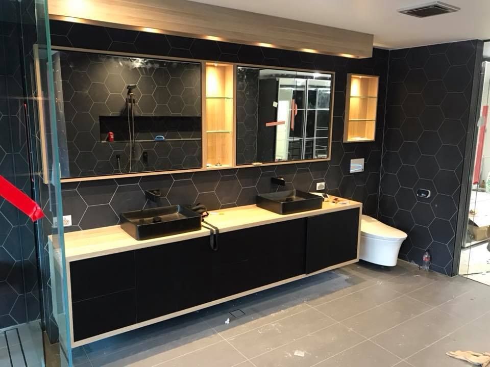 Modern bathroom vanity with dual black sinks, light wood countertop, hexagonal black wall tiles, and recessed lighting. — Michael Duncan Constructions Pty Ltd in Burleigh Heads, QLD
