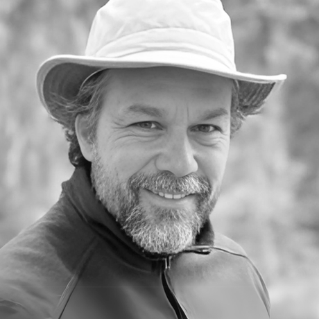 Man wearing a hat and jacket, smiling at the camera.