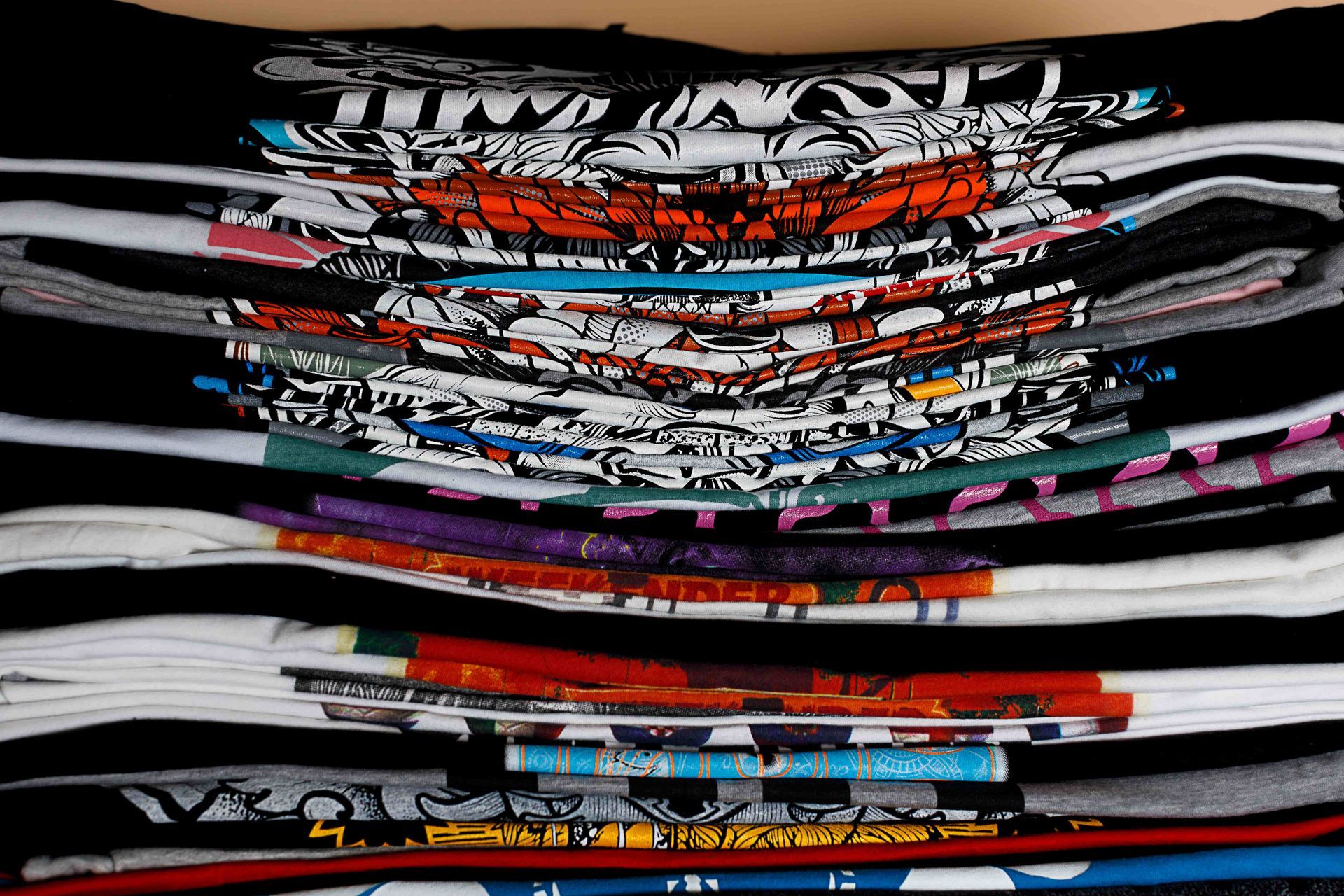 A stack of t-shirts with one that says ' tmw ' on it