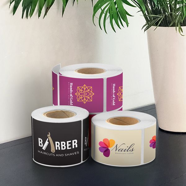 Three rolls of stickers are sitting on a table next to a potted plant.