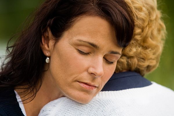 a woman is hugging another woman with her eyes closed .