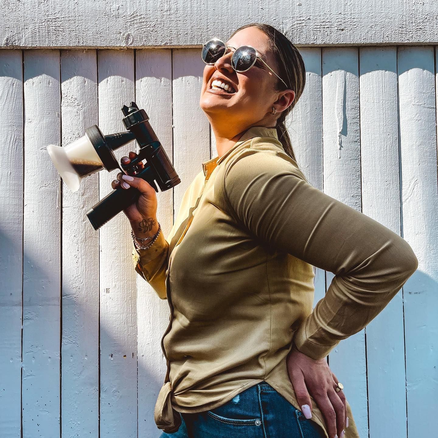 Two smiling women posing with spray bottles in front of a gray wall