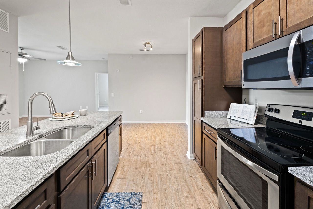 Modern kitchen with granite countertops, double sink, and stainless steel appliances.