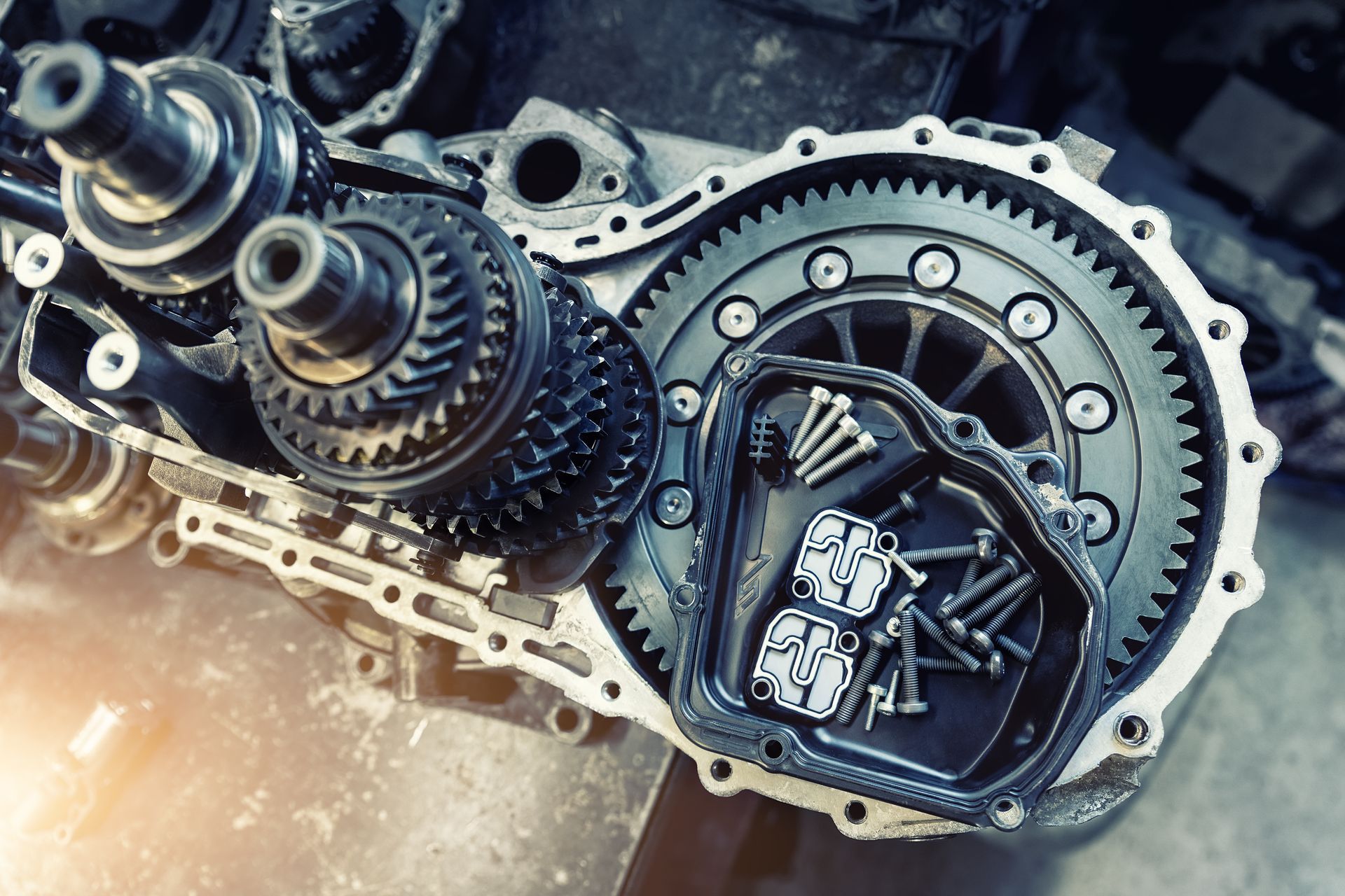 Internal view of an open car gearbox with stacked metal gears and bolts gathered in a tray during mechanical repairs. Internal view of an open car gearbox with stacked metal gears and bolts gathered in a tray during mechanical repairs.