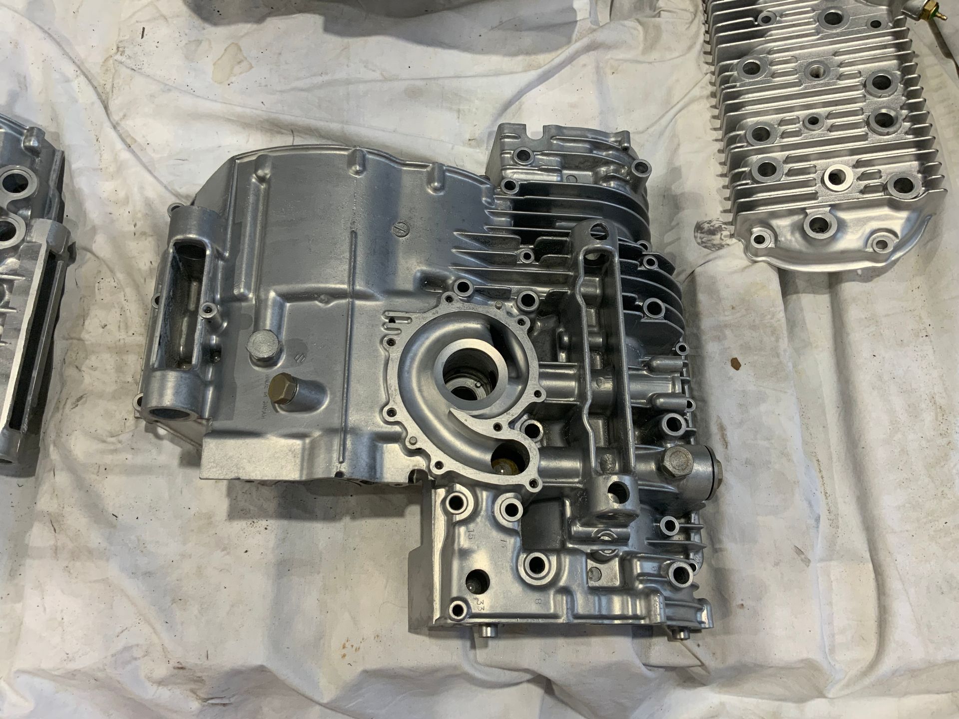 Cleaned aluminum engine crankcase and cylinder head parts resting on a white surface. Cleaned aluminum engine crankcase and cylinder head parts resting on a white surface.