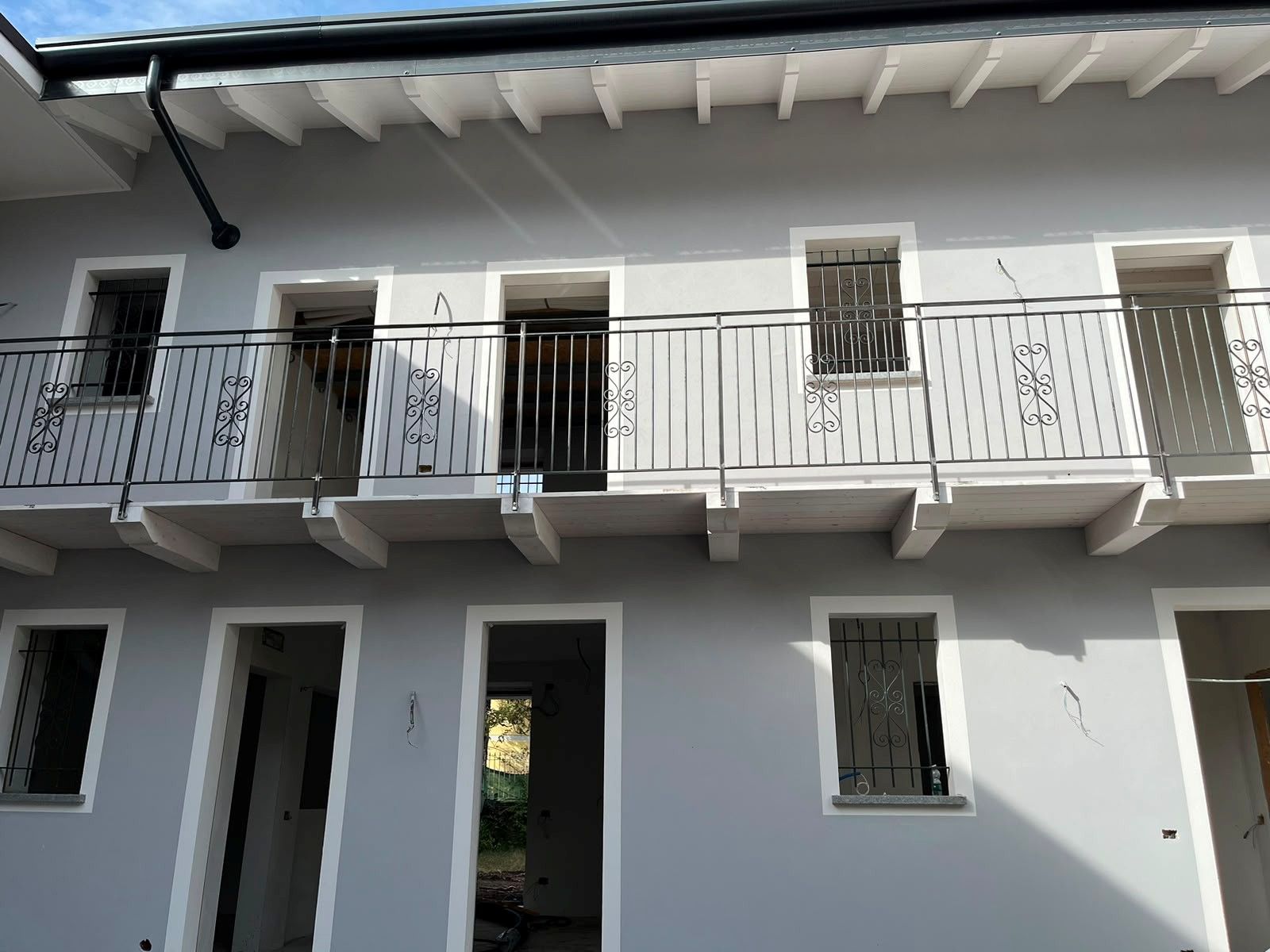 Edificio residenziale bianco a due piani con balconi e finestre con inferriate, esposto alla luce naturale.