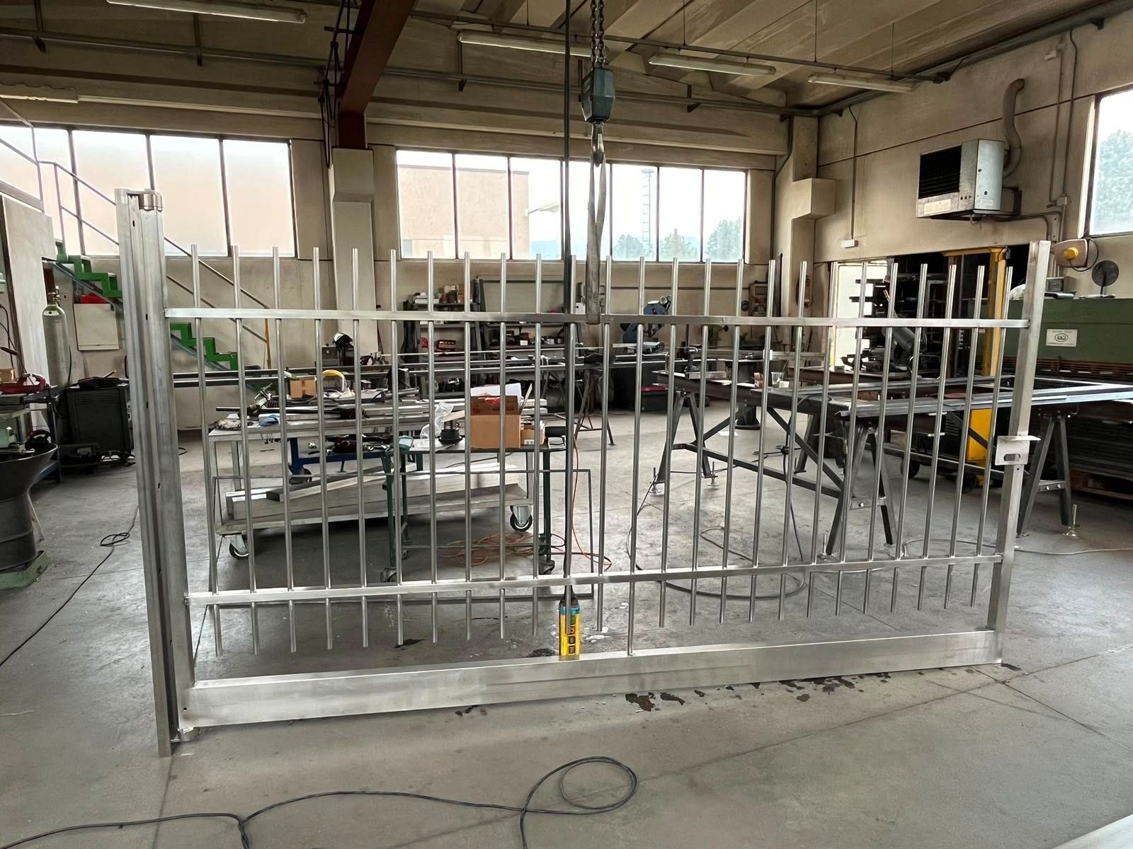 Officina industriale con un grande cancello metallico in fase di costruzione all'interno di un magazzino.