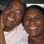 Two smiling people close together. Man in glasses and a light shirt, woman in a white top.